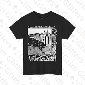 Peut inclure: T-shirt noir avec une illustration en noir et blanc d'un château et d'un paysage dans un cadre décoratif. Le motif comprend des arbres, des bâtiments et des éléments floraux. Le t-shirt a un col rond et des manches courtes.