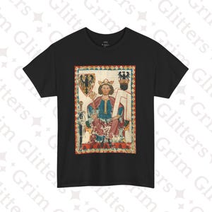 Puede incluir: Camiseta negra con una ilustración vintage de un rey sentado en un trono. El rey lleva una túnica roja y azul y una corona. Sostiene una espada en su mano derecha y un cetro en su mano izquierda. La ilustración está rodeada por un borde decorativo.