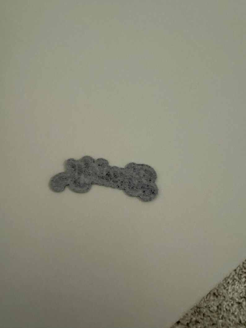 May include: A gray felt bone-shaped dog toy.