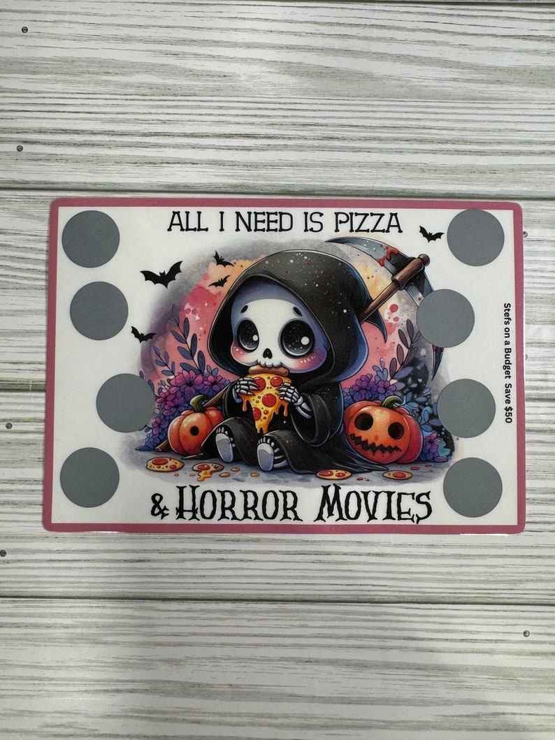 May include: A Halloween-themed card with a cartoon skeleton wearing a black hooded robe and eating pizza. The card says "All I need is pizza & horror movies".