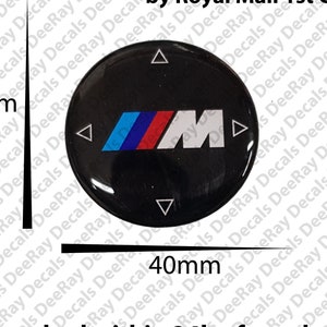 May include: A black and white 40mm round sticker with a blue, red, and white BMW logo and four directional arrows. The sticker says "Made in UK Premium Quality" and "Dispatched within 24h of purchase."