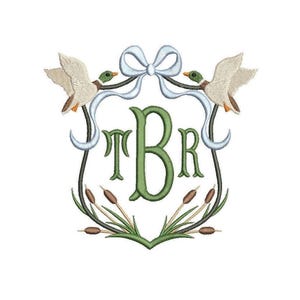 May include: Embroidered emblem featuring a shield shape with the letters TBR in green. Two ducks fly above a light blue bow. Reeds and cattails are at the bottom of the shield. The design is on a white background.