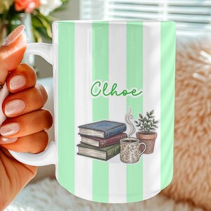 Personalized ceramic mug featuring a green-striped background, a custom name, stacked books, a coffee cup, and a plant illustration.