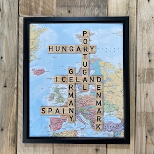 May include: A framed map of Europe with the names of European countries spelled out using letter tiles. The tiles are arranged in a crossword puzzle format.