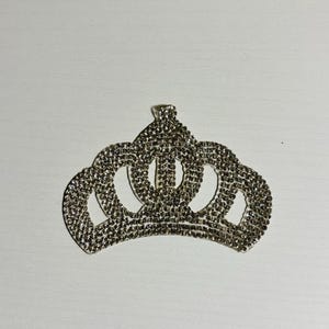 May include: A silver crown made of rhinestones. The crown has a pointed top and five points.