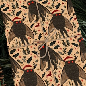 Puede incluir: Papel de regalo con un patrón repetido de una criatura parecida a una polilla con un gorro de Papá Noel y ojos rojos. El fondo es de color beige con ilustraciones navideñas. El regalo está atado con hilo.