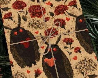 May include: Gift-wrapped package featuring a repeating pattern of black moth-like creatures with red hearts and eyes, red and white flowers, and small red hearts on a tan background. The package is tied with a silver-gray string.