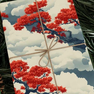 May include: Gift wrap featuring a Japanese-inspired design with a red and blue tree and white clouds on a cream background. The paper is tied with a brown twine bow.