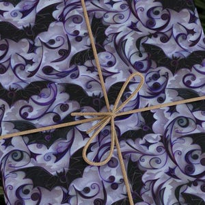 May include: Purple and black patterned wrapping paper with a brown ribbon tied in a bow.