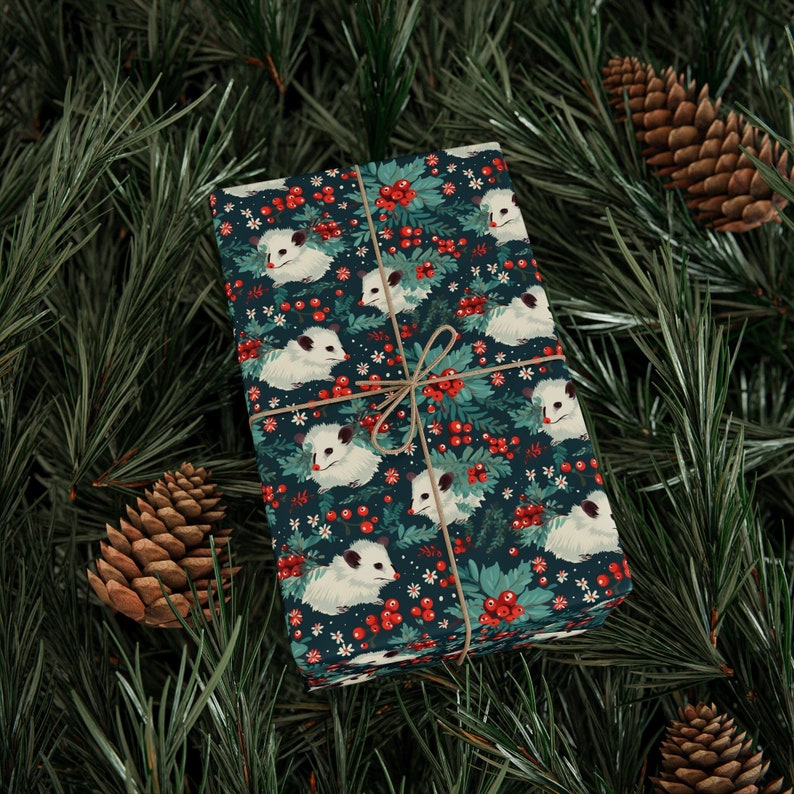May include: A gift wrapped in blue wrapping paper with a pattern of white opossums, red berries, and green leaves. The paper is tied with twine.
