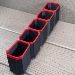 May include: A black organiser with six compartments, each with a red trim, for storing small items.