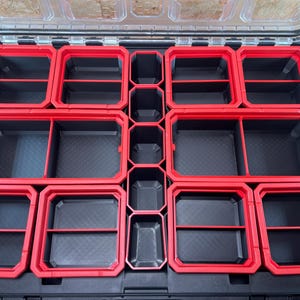 May include: A black toolbox with red dividers. The toolbox has multiple compartments for organising small items.