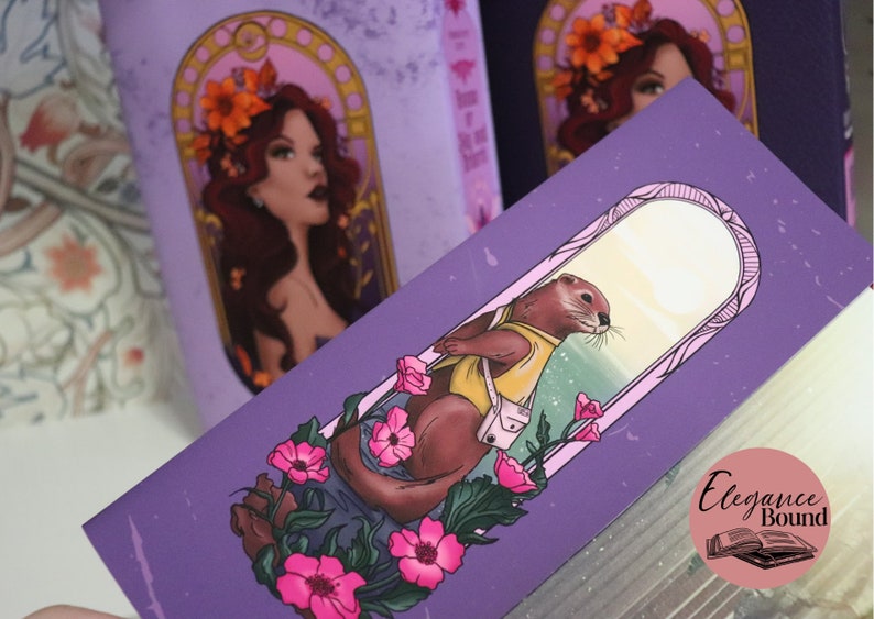 May include: Purple bookmark featuring an illustration of an otter wearing a yellow shirt and a white bag, surrounded by pink flowers. The bookmark also features a woman with flowers in her hair. The Elegance Bound logo is visible.