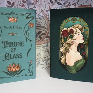 Pode incluir: Dois livros de capa dura. O livro da esquerda &eacute; verde-azulado com o t&iacute;tulo "Throne of Glass" e o nome do autor. O livro da direita &eacute; verde escuro com um retrato de mulher e rosas vermelhas. Ambos os livros t&ecirc;m elementos florais decorativos.
