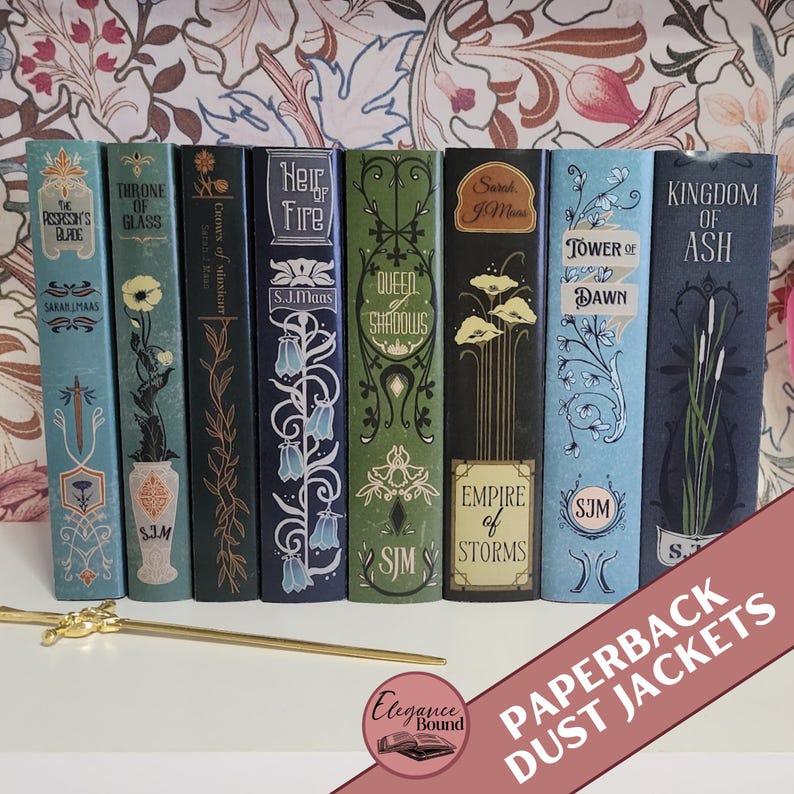 Pode incluir: Uma cole&ccedil;&atilde;o de sobrecapas de livros de bolso com t&iacute;tulos como "Throne of Glass" e "Kingdom of Ash". As capas apresentam desenhos florais e geom&eacute;tricos em tons de azul, verde e preto. Um marcador dourado est&aacute; em frente aos livros.