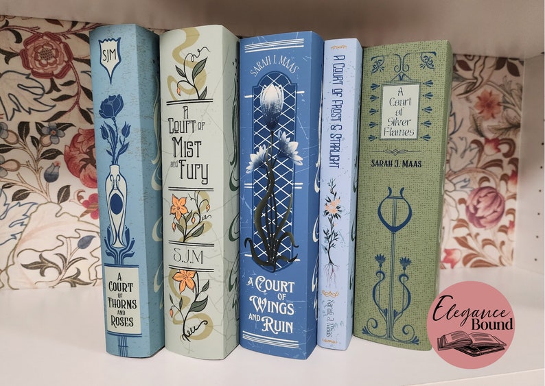 May include: A collection of fantasy novels with decorative covers. The books are in shades of blue and green, with floral and art nouveau-inspired designs. Titles include "A Court of Thorns and Roses" and "A Court of Wings and Ruin."