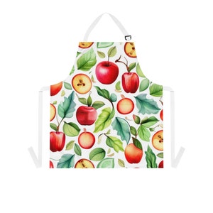 Op de afbeelding: Witte keukenschort met een patroon van rode appels en groene bladeren.