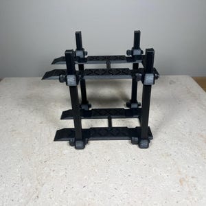 Puede incluir: Un elevador de coches de metal negro para coches de modelismo. El elevador tiene dos niveles y est&aacute; hecho de pl&aacute;stico.