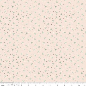 May include: A light peach-colored fabric with a repeating pattern of small green leaf shapes and tiny black dots. The fabric is measured with a ruler in inches.