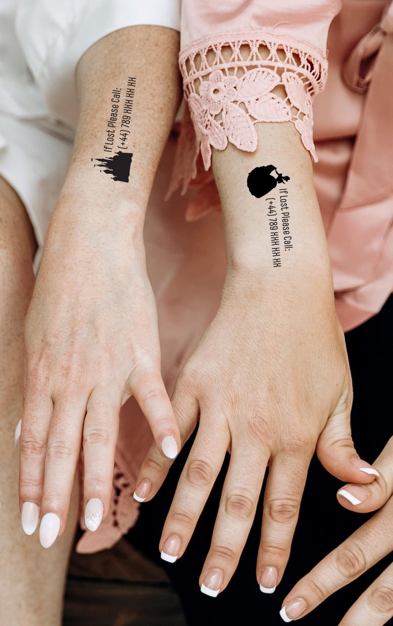 May include: Two temporary tattoos applied to the inner wrists. One tattoo features a black silhouette of a castle with the text "If Lost Please Call: (+44) 789 XXX XX XX". The other tattoo shows a black silhouette of a carriage with the same text.