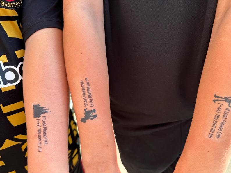 May include: Three forearms each featuring a black temporary tattoo. Each tattoo displays a small black silhouette of a castle or animal above the text: If Lost Please Call: (+44) 789 HHH HH HH. The tattoos are applied to the skin of three individuals.