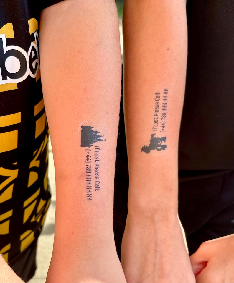 May include: Two temporary tattoos on skin. The left tattoo features a black castle silhouette with the text: If Lost Please Call: (+44) 789 HHH HH HH. The right tattoo shows a black cartoon character silhouette with the text: If Lost Please Call: (+44) 789 HHH HH HH.