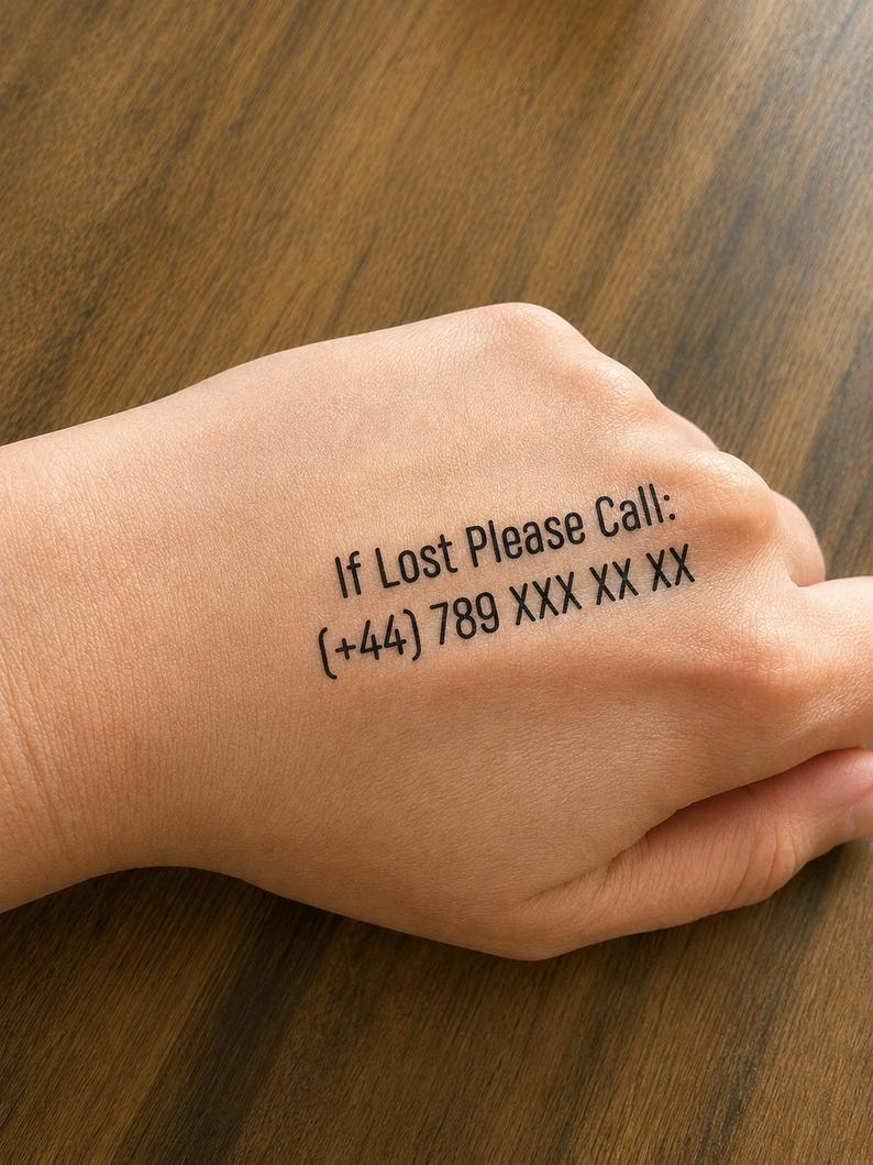 May include: A temporary tattoo applied to the skin featuring black text that reads: If Lost Please Call: (+44) 789 XXX XX XX. The lettering is printed in a clean, sans-serif font, providing a clear and legible message for identification purposes.