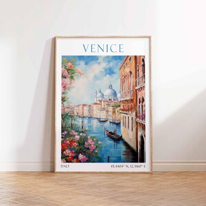 May include: Framed art print of Venice, Italy, featuring a canal scene with buildings, boats, and floral accents. The word "VENICE" is at the top, with "ITALY" and coordinates at the bottom. The artwork is in a wooden frame.