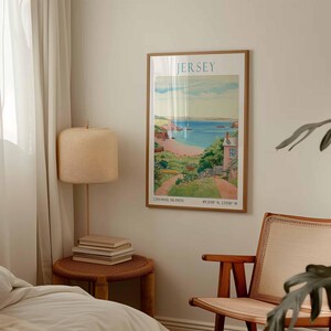 May include: A framed poster depicting a coastal scene, with the word "JERSEY" at the top. The poster includes the text "CHANNEL ISLANDS" and coordinates at the bottom. The frame is a light brown colour. The image is reminiscent of a vintage travel poster.
