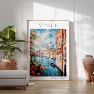 May include: A framed art print of Venice, Italy, featuring a canal scene with gondolas, buildings, and a blue sky. The artwork has a gold frame and is displayed with a potted plant, ottoman, and decorative vases.