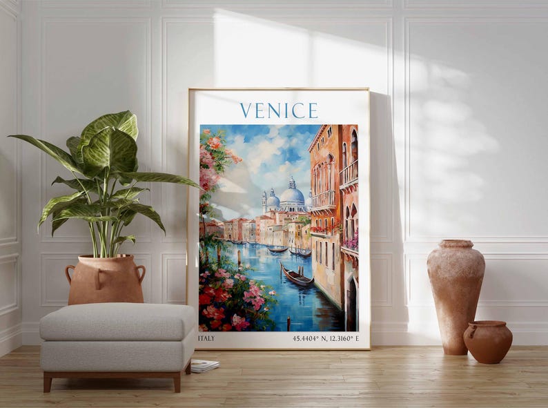 May include: A framed art print of Venice, Italy, featuring a canal scene with gondolas, buildings, and a blue sky. The artwork has a gold frame and is displayed with a potted plant, ottoman, and decorative vases.