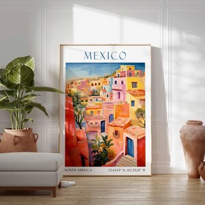 Op de afbeelding: Een kleurrijk schilderij van een stadsgezicht in Mexico. De gebouwen zijn geschilderd in tinten roze, geel, oranje en rood. Het schilderij is ingelijst in een gouden lijst en heeft de tekst "MEXICO" bovenaan. De tekst "NORTH AMERICA" en de co&ouml;rdinaten "23.6345&deg; N, 102.5528&deg; W" staan onderaan het schilderij.