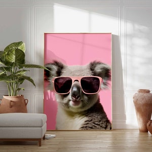 May include: A koala wearing pink sunglasses against a pink background. The koala is looking directly at the camera.