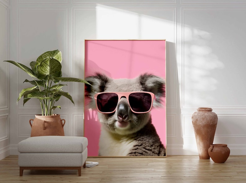 May include: A koala wearing pink sunglasses against a pink background. The koala is looking directly at the camera.