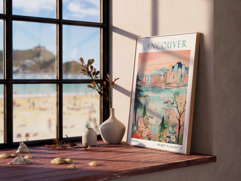 May include: A framed poster with a vintage travel illustration of Vancouver, Canada. The poster features a cityscape with buildings, a body of water, and boats. The poster is hanging on a wall next to a window with a view of a beach.