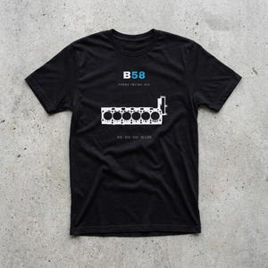 May include: A black short-sleeved t-shirt featuring a white graphic of an engine block outline. The text B58 is printed in blue and white above the graphic, with the words TURBO INLINE-SIX and M140, M240, M340, A90 SUPRA printed in white below.