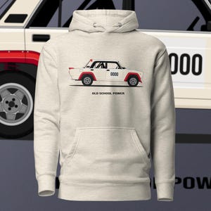 Puede incluir: Sudadera con capucha de color beige claro con un gráfico de un coche vintage blanco con detalles rojos. El coche tiene el número "0000" y el texto "OLD SCHOOL POWER". La sudadera tiene un bolsillo delantero y una capucha.