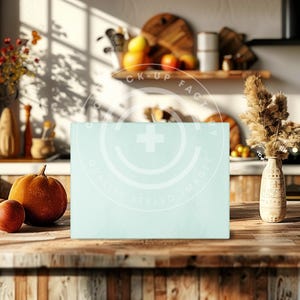 Op de afbeelding: Een lichtblauw rechthoekig bord met de tekst "Mock-Up Factory Quality Styled Images" in een witte cirkel met een plusteken in het midden. Het bord staat op een houten tafel met een pompoen en een rode appel ervoor.
