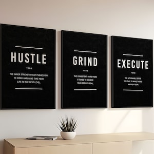 Puede incluir: Tres carteles motivacionales enmarcados en negro con texto blanco. Los carteles están colgados en una pared blanca. El primer cartel dice "Hustle" y lo define como "la fuerza interior que te impulsa a trabajar duro y llevar tu vida al siguiente nivel". El segundo cartel dice "Grind" y lo define como "el trabajo duro constante que se necesita para lograr tu objetivo deseado". El tercer cartel dice "Execute" y lo define como "los pasos viables que tomas para hacer que las cosas sucedan hoy".