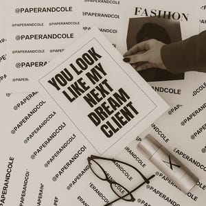 Peut inclure: Image sépia avec divers éléments. Une feuille de papier avec le texte "YOU LOOK LIKE MY NEXT DREAM CLIENT" est au centre. D'autres papiers avec le texte "@PAPERANDCOLE" sont éparpillés. Une paire de lunettes et un flacon de spray argenté sont également visibles.