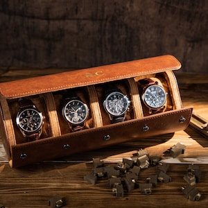 May include: A brown leather watch roll with four watches inside. The watches have black and brown leather bands and silver and black watch faces. The watch roll is open, revealing the watches. The initials "E.C." are embossed on the top.