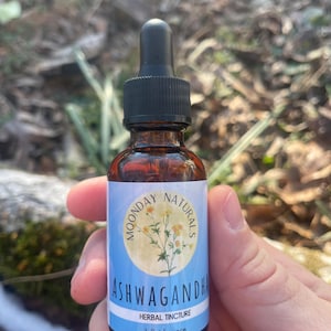 May include: A brown glass bottle with a black dropper top. The label reads "Moonday Naturals Ashwagandha Herbal Tincture 1 fluid ounce".