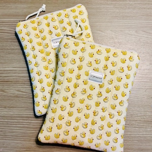 May include: Two yellow fabric pouches with a repeating pattern of yellow rubber ducks. Each pouch has a zipper closure and a white cord loop. The text "99PRESS" is printed on a white label on the front of one pouch.