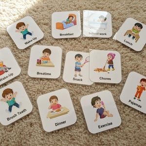 May include: A set of square cards illustrating daily routines, each with a cartoon child. Activities shown include "Wake-Up," "Breakfast," "School work," "Lunch," "Brush Teeth," "Dinner," "Exercise," "Chores," "Snack," "Breatime," and "Pajamas."