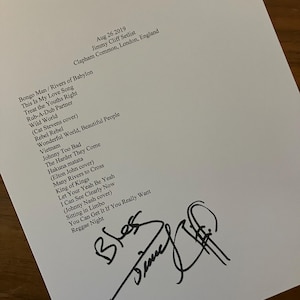 以下が含まれることがあります： 2019年8月26日、ロンドンで開催されたジミー・クリフのコンサートのセットリストが印刷された白い紙。 「Bongo Man」、「Wild World」、「Rebel Rebel」などの曲がリストに掲載されています。 黒いインクでサインされています。