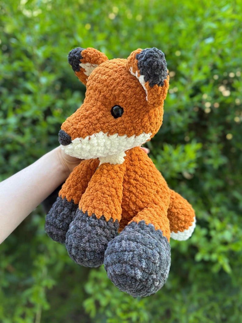 Puede incluir: Un peluche de zorro hecho a mano con ganchillo. El zorro presenta hilo naranja, blanco y gris. El zorro tiene ojos negros y un hocico blanco. Las orejas tienen puntas negras. El peluche es suave y tierno.