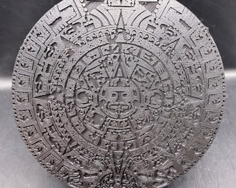 May include: A black circular relief sculpture with intricate designs and symbols. The sculpture is reminiscent of the Aztec calendar stone.