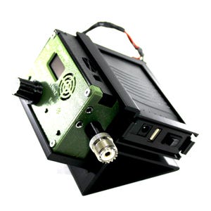 May include: A black and olive green electronic device featuring a front panel with a circular knob, a small digital display, a circular vent, and a metallic connector. The side panel includes a power port, a USB port, and a toggle switch.