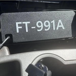 May include: A black plastic tag with white text that reads "FT-991A".