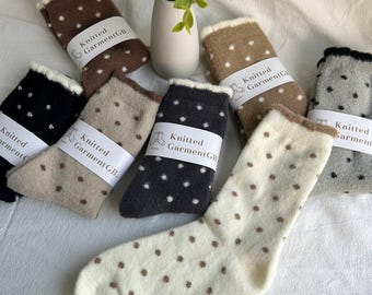 May include: Five pairs of fuzzy socks with brown polka dots. The socks are in various colors, including brown, black, white, and gray. The socks have a white label that says "Knitted GarmentGB."